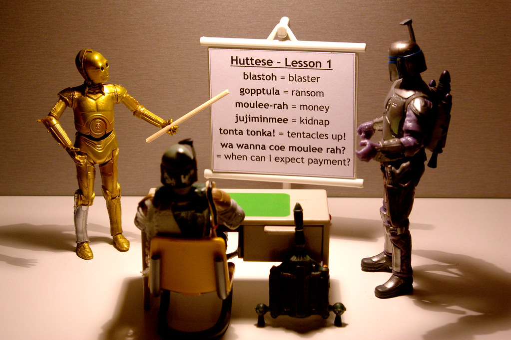 C3PO from Star Wars giving a language lesson with a whiteboard and pointer in hand.