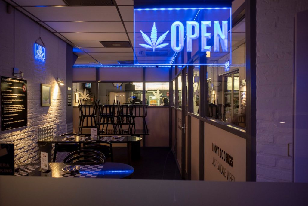 blue and white marijuana store with blue neon open sign.