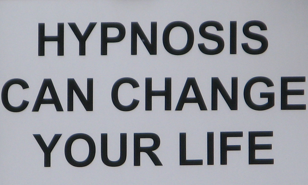 A white sign with black letters which reads: "Hypnosis Can Change Your Life".