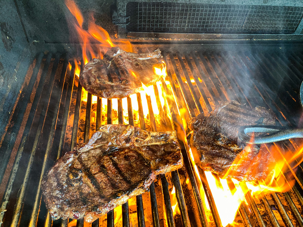 Steaks cooking on a hot grill.