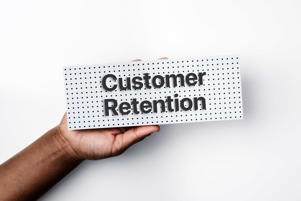 Hand holding sign which reads: "Customer Retention".