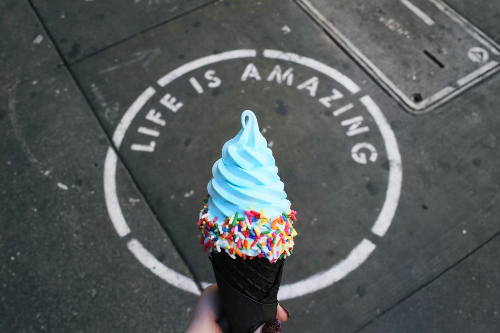 ice cream cone in front of a sign which reads: "Life is Amazing"